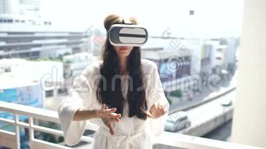 女士穿着浴袍，戴着虚拟现实耳机站在酒<strong>店</strong>客房阳台上，有VR<strong>体验</strong>
